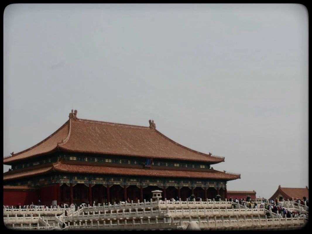 A red palace hall with a sweeping tiled roof above white stone terraces