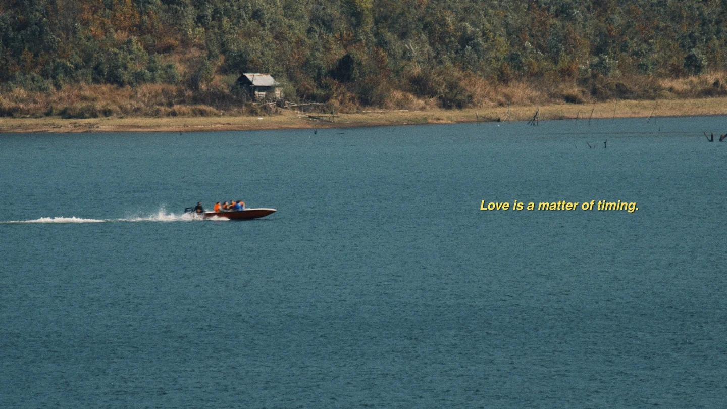 A small red speedboat crossing a blue lake, with a yellow subtitle beside it