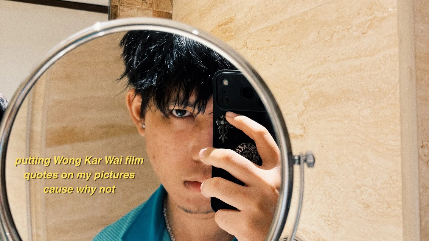 A self-portrait in a round mirror, phone held over one eye, with a yellow subtitle across it