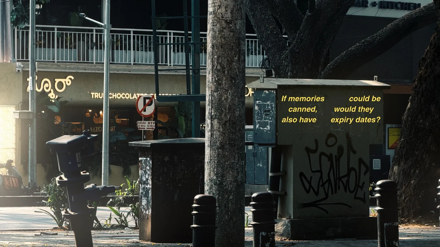 A shuttered street stall covered in graffiti beside a tree, with a yellow subtitle on its side